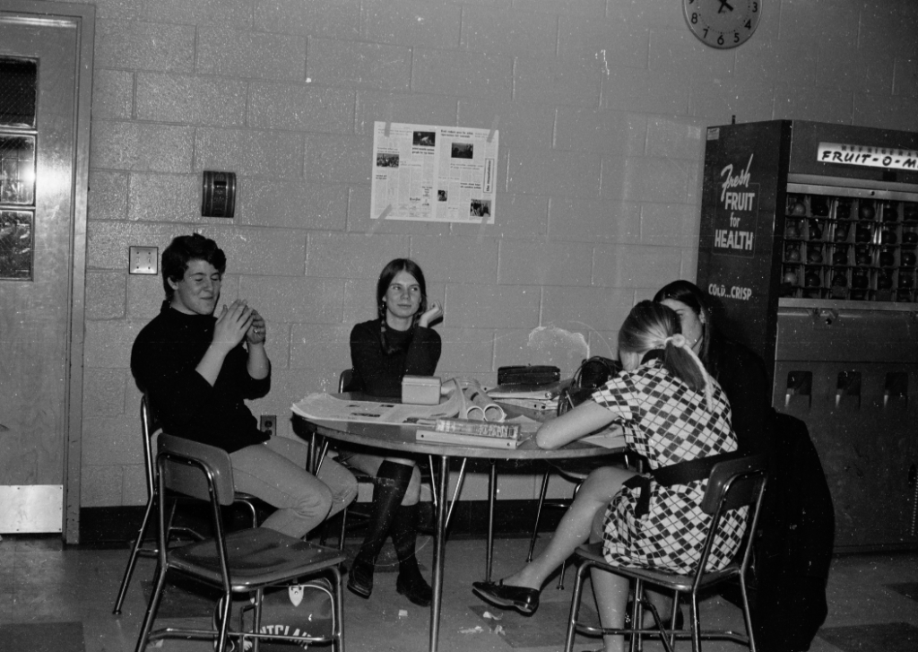 William Frake and students sitting at a Table in Lunchroom with Fruit o matic to the right