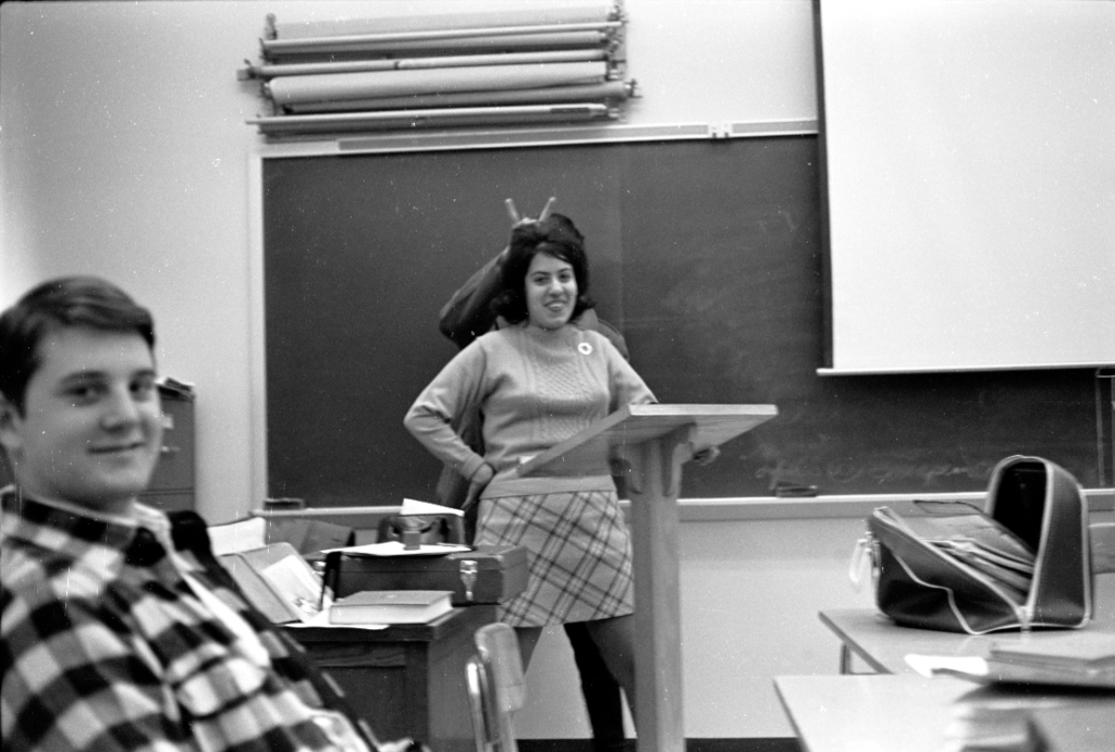 Teacher in classroom with student behind her doing bunny ears