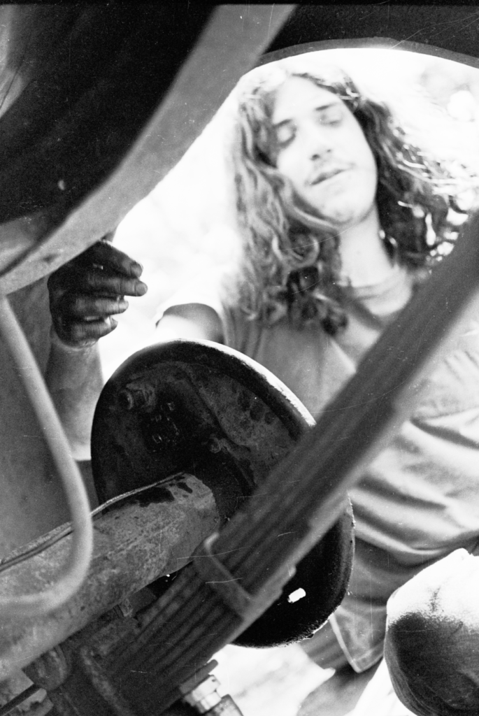 Greg Sullivan, blurry fixing brakes of pickup truck. Probably later around 1973.