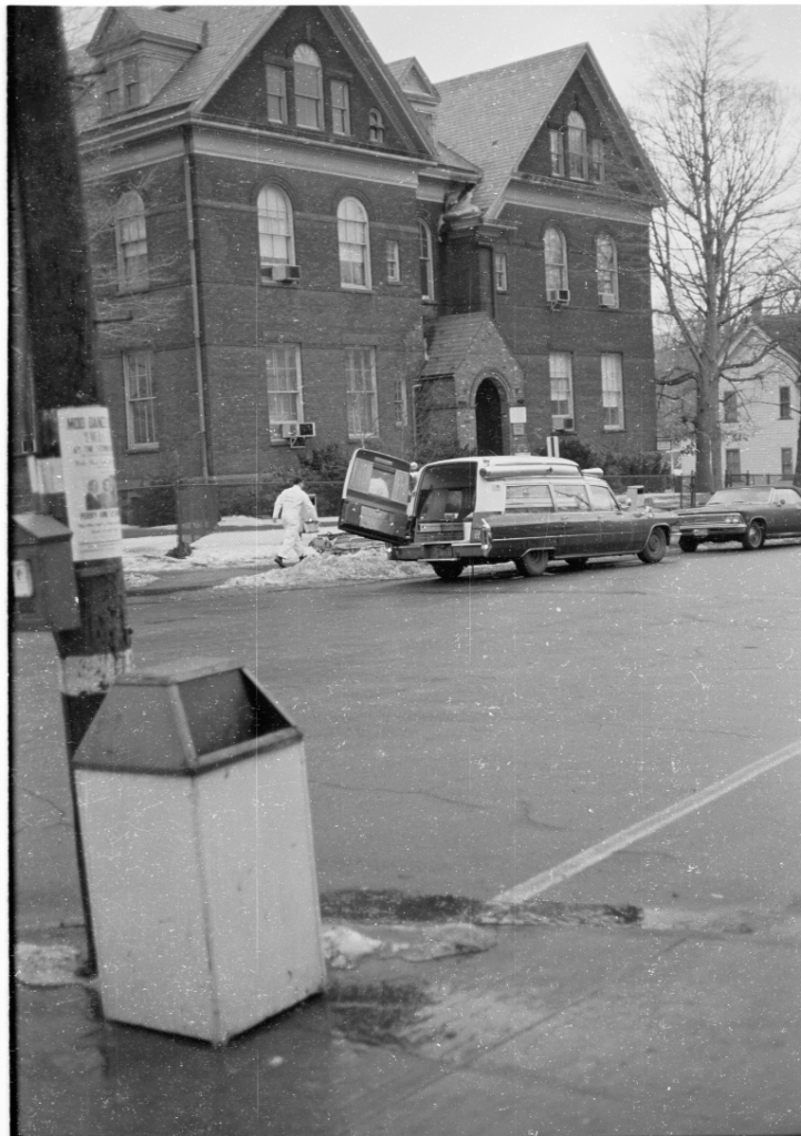 Ambulance with rear door open in front of brick building.